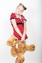 Beautiful young girl dressed in a red dress with white polka dots holding a teddy bear Royalty Free Stock Photo