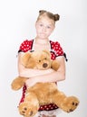 Beautiful young girl dressed in a red dress with white polka dots holding a teddy bear Royalty Free Stock Photo