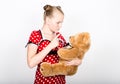 Beautiful young girl dressed in a red dress with white polka dots holding a teddy bear Royalty Free Stock Photo