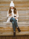 Beautiful young girl drinking coffee, tea from plastic mug in autumn, winter and talking on mobile phone. Woman with long hair Royalty Free Stock Photo