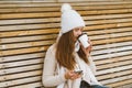 Beautiful young girl drinking coffee, tea from plastic mug in autumn, winter and talking on mobile phone. Woman with long hair Royalty Free Stock Photo