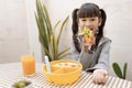 Beautiful young girl eating breakfast and orange juice on the holiday home table. Royalty Free Stock Photo