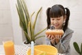 Beautiful young girl eating breakfast and orange juice on the holiday home table. Royalty Free Stock Photo