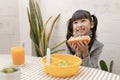 Beautiful young girl eating breakfast and orange juice on the holiday home table. Royalty Free Stock Photo