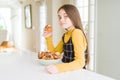 Beautiful young girl eating chocolate chips muffins with a confident expression on smart face thinking serious