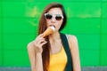 Beautiful young girl eating ice cream near the green wall. Royalty Free Stock Photo