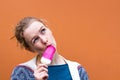 Beautiful and young girl eats a pink hue ice cream and enjoys. The girl looked up, appreciating the taste of ice cream.