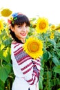 Beautiful young girl in embrodery holding a sunflower on a plan Royalty Free Stock Photo