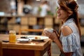 Beautiful young girl enjoying cup of coffee alone. Cheerful young woman in cafe