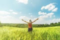 Beautiful young girl enjoying hot summer day in the middle of the field of hops with hands wide open and big white hat