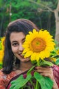 Beautiful young girl enjoying nature on the field of sunflowers. Girl in park smiling and covering face with sunflower. Royalty Free Stock Photo