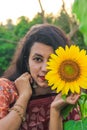 Beautiful young girl enjoying nature on the field of sunflowers. Girl in park smiling and covering face with sunflower. Royalty Free Stock Photo