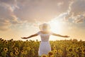 Beautiful young girl enjoying nature on the field of sunflowers at sunset Royalty Free Stock Photo