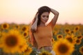 Beautiful young girl enjoying nature on the field of sunflowers at sunset. Summertime. Attractive brunette woman with long healthy Royalty Free Stock Photo