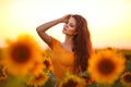 Beautiful young girl enjoying nature on the field of sunflowers at sunset. Summertime. Attractive brunette woman with long healthy Royalty Free Stock Photo