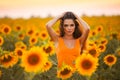 Beautiful young girl enjoying nature on the field of sunflowers at sunset. Summertime. Attractive brunette woman with long healthy Royalty Free Stock Photo