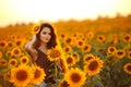 Beautiful young girl enjoying nature on the field of sunflowers at sunset. Summertime. Attractive brunette woman with long healthy Royalty Free Stock Photo