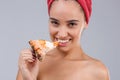 Beautiful girl,with bare shoulders and with a towel on her head, appetizingly eating a slice of pizza.