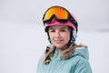 A beautiful young girl in an extreme sports suit, a hat and a helmet with a mask on the winter slope is holding alpine Royalty Free Stock Photo