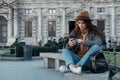 Beautiful young girl in a fashionable brown hat looks at the phone