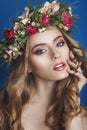 Beautiful young girl with a floral ornament in her hair on a blue background. Woman in wreath of flowers.Beauty Face. Fashion Royalty Free Stock Photo