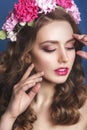 Beautiful young girl with a floral ornament in her hair on a blue background. Woman in wreath of flowers.Beauty Face. Fashion