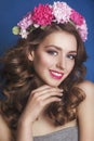 Beautiful young girl with a floral ornament in her hair on a blue background. Woman in wreath of flowers.Beauty Face. Fashion