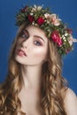 Beautiful young girl with a floral ornament in her hair on a blue background. Woman in wreath of flowers.Beauty Face. Fashion Royalty Free Stock Photo