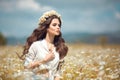 Beautiful young girl with flower enjoying in chamomile field. Carefree happy brunette woman with chaplet on healthy wavy hair Royalty Free Stock Photo