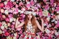 A beautiful young girl with flowers bouquet near a floral wall. Royalty Free Stock Photo