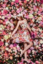 A beautiful young girl with flowers bouquet near a floral wall. Royalty Free Stock Photo