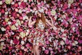 A beautiful young girl with flowers bouquet near a floral wall. Royalty Free Stock Photo