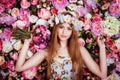 A beautiful young girl with flowers bouquet near a floral wall. Royalty Free Stock Photo