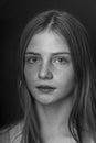 Beautiful young girl with freckles indoors on a black background, close up portrait. Black and white Royalty Free Stock Photo