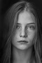 Beautiful young girl with freckles indoors on a black background, close up portrait. Black and white Royalty Free Stock Photo