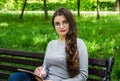 Beautiful young girl in glasses with a notebook and pen in her hands sits on a bench in the park and looks at the camera. Close-up Royalty Free Stock Photo