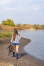 A beautiful young girl goes fishing. A girl with a fishing rod and a cage in hand is walking along the lake Royalty Free Stock Photo