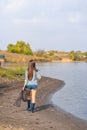 A beautiful young girl goes fishing. A girl with a fishing rod and a cage in hand is walking along the lake Royalty Free Stock Photo