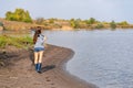 A beautiful young girl goes fishing. A girl with a fishing rod and a cage in hand is walking along the lake Royalty Free Stock Photo