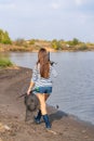 A beautiful young girl goes fishing. A girl with a fishing rod and a cage in hand is walking along the lake Royalty Free Stock Photo