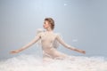 Beautiful young girl, graceful ballerina in image of angel with wings sitting on cloud  on white gray studio Royalty Free Stock Photo