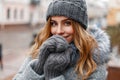 Beautiful young girl in a gray knitted hat and mittens, outdoors. Royalty Free Stock Photo