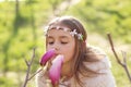 Beautiful young girl with handmade hair wreath on her head looking at magnolia flower and smelling it aroma Royalty Free Stock Photo