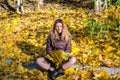 The beautiful young girl a happy woman smiling and holding a yellow maple leaves walking in autumn park Royalty Free Stock Photo