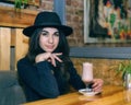 Beautiful young girl in hat drinking coffee in cafe Royalty Free Stock Photo