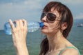 beautiful young girl having fun drinking water from a plastic bottle, in hot weather near the sea Royalty Free Stock Photo