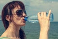 Beautiful young girl having fun drinking water from a plastic bottle, in hot weather near the sea, toned Royalty Free Stock Photo