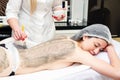 Beautiful young girl having seaweed cosmetic mask and body massage with scrub in spa salon Royalty Free Stock Photo
