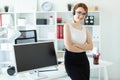 A beautiful young girl in headphones with a microphone sat on the desk in the office. Next to the girl there is a Royalty Free Stock Photo