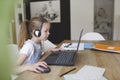 Beautiful young girl with headset is sitting in front of her laptop during corona time and is having video call Royalty Free Stock Photo